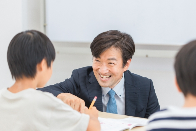 塾の男性講師が小学生の男の子に勉強を教えている画像